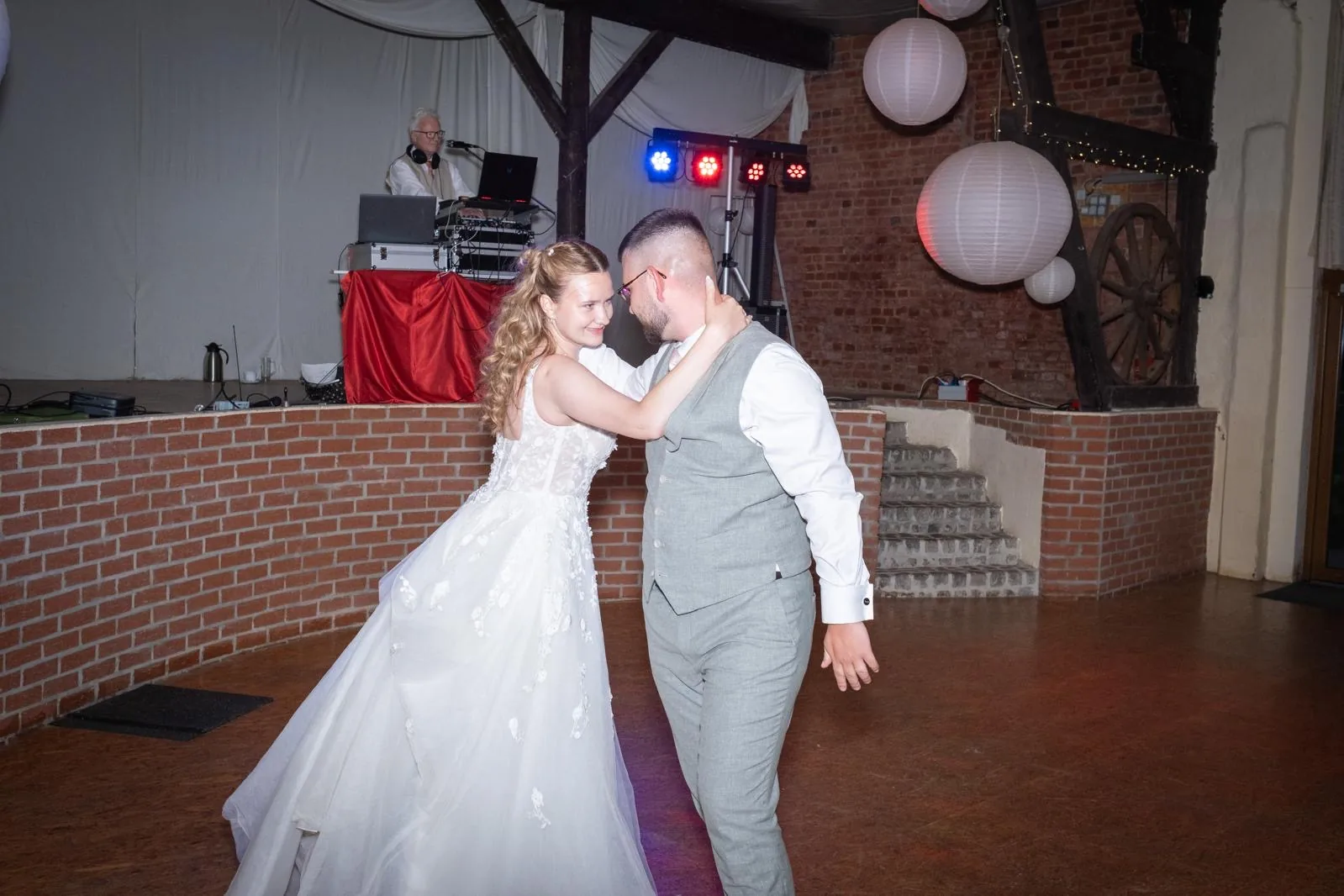 Hochzeitspaar auf der Tanzfläche, DJ im Hintergrund